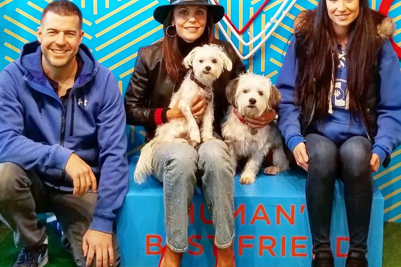 Bethenny Frankel, in a black hat, with Biggy and Smallz on her lap, seated between Steve Del Savio and a Pack Leader Dogs trainer.