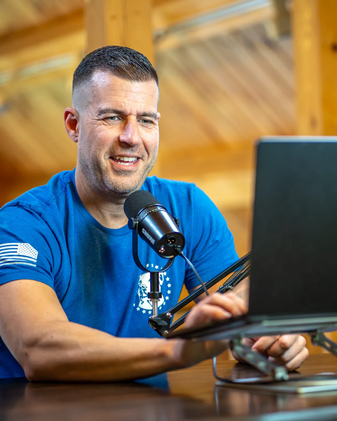 Steve Del Savio at his desk with a microphone and laptop, smiling during a virtual session.