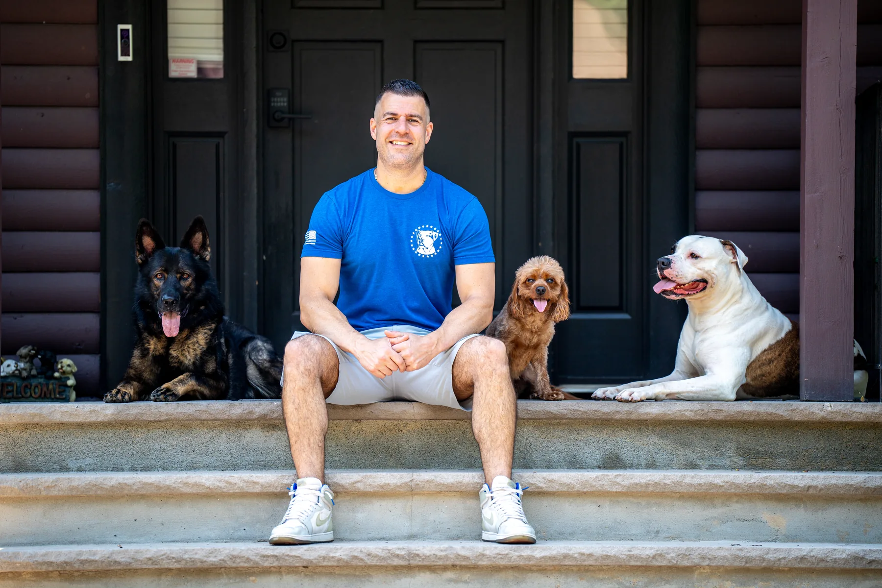 Steve Del Savio seated on the lodge steps with three dogs lying calm beside him.
