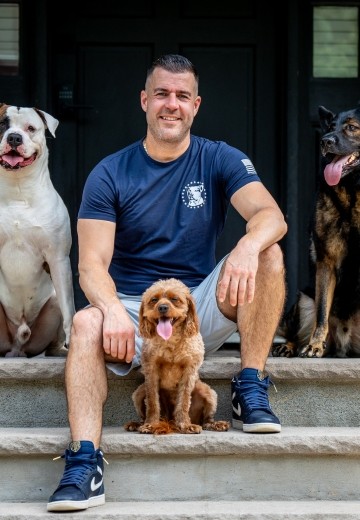 Steve Del Savio seated on the lodge steps with three calm dogs resting beside him